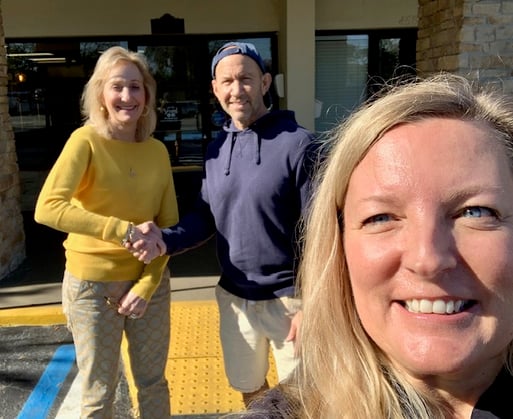 Selfie of Certified Restaurant Broker® April Greenwood with the Seller, Tammy (left) shaking buyer, Mark's (right) hand in front of The Bakery.